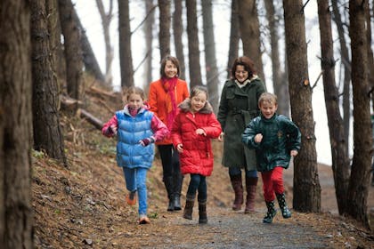 two woman and children walking in forest