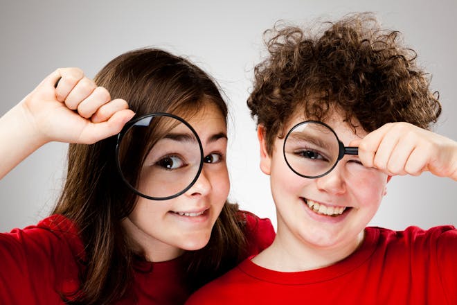 A girl and a boy both with magnifying glasses