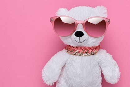 White teddy bear wearing pink sunglasses