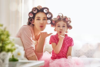 Child and mother with rollers in their hair, blowing kisses