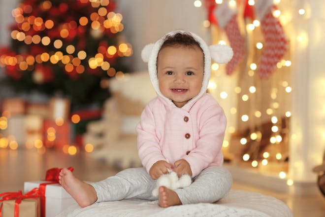smiling baby girl sitting in front of Christmas lights