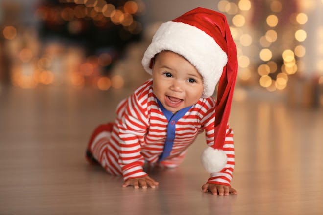 crawling baby wearing a santa hat