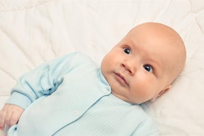 Baby lying on back looking surprised