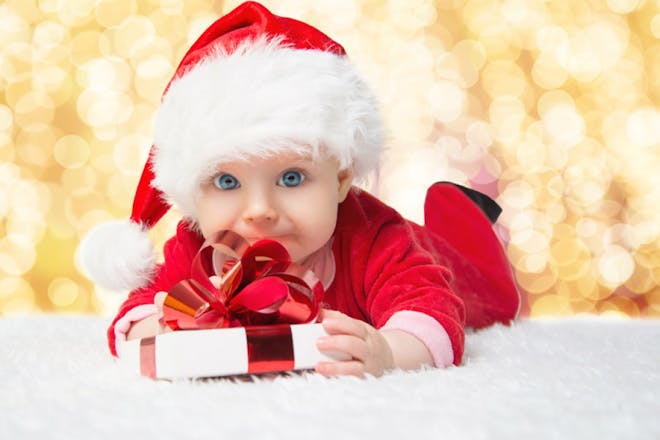 baby in christmas suit holding present