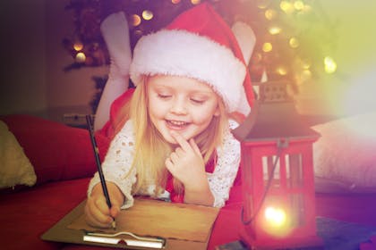 girl wearing christmas hat and writing a letter