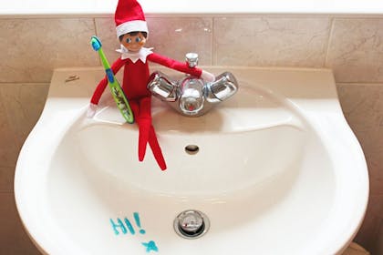 Elf on the Shelf holding toothbrush writes 