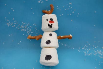 Snowman treat made out of marshmallows, pretzels and icing for Frozen birthday party