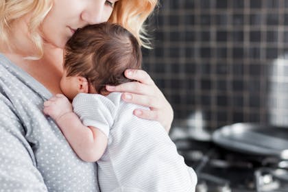 New mum in kitchen with newborn baby