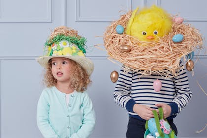 Two kids wearing birds' nest Easter bonnets