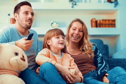 Family watching TV together, laughing