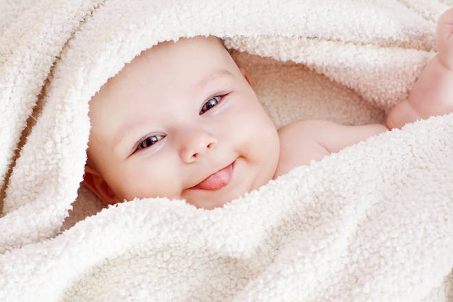 Cute baby girl, wrapped in fluffy towel, poking tongue out