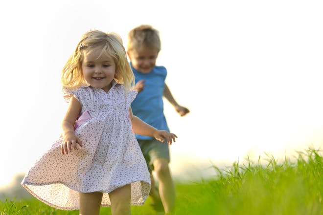 young girl and boy running outside in the grass