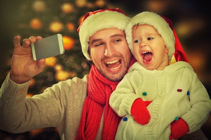 dad taking a selfie with his baby daughter wearing santa hats