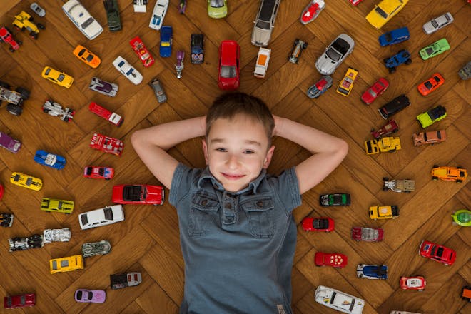 boy surrounded by collection of toy cars