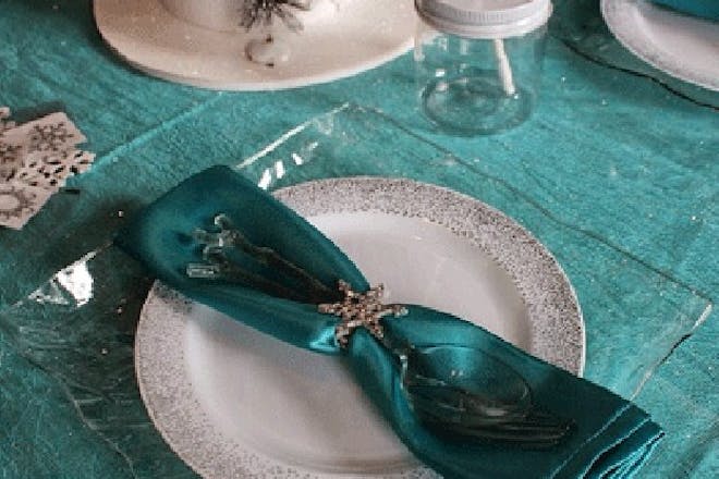 Teal napkin on sparkly plate with wintry decorations around for Frozen themed party tableware