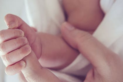 adult hand holding a newborn hand