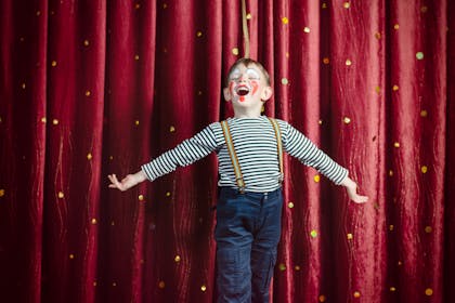 Child dressed as a clown performing on stage