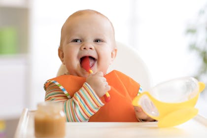 Little girl eating in high chair