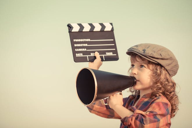 Kid dressed as vintage film director with megaphone, clapperboard and a flat cap hat