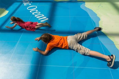 Two kids sprawl on the huge world map at the National Maritime Museum in Greenwich, London 