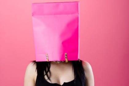 woman with pink bag over her head on pink background