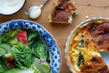 quiche next to bowl of salad