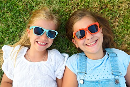 girls wearing sunglasses and lying on grass
