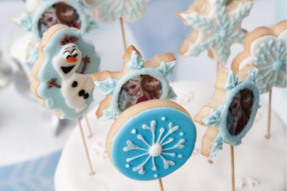 Shortbread biscuits with icing decoration showing Olaf, Elsa, Anna and a snowflake for Frozen party
