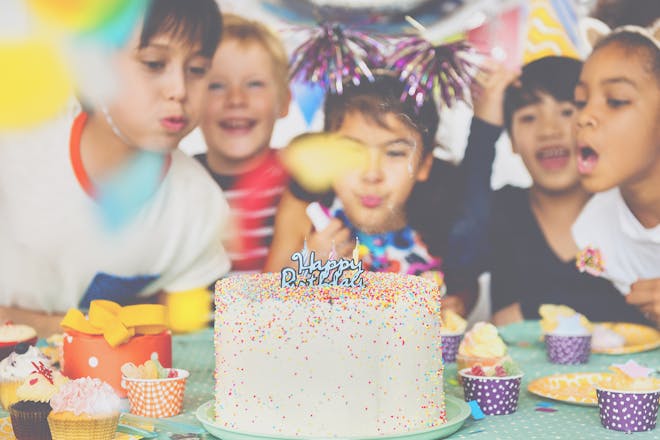 Children surrounding a birthday cake and blowing out the candles