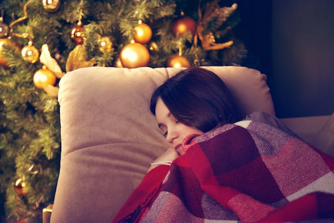 Girl sleeping next to the Christmas tree 