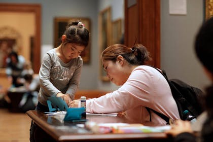 A young girl and her mother engage in a craft activity at the National Portrait Gallery in London