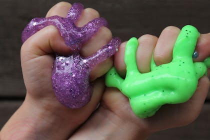 Kids' hands squeezing brightly coloured slime