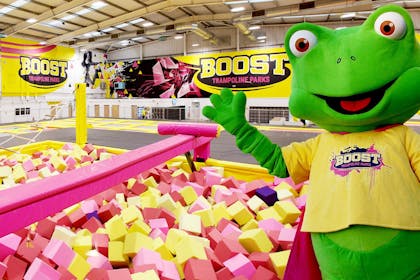 Frog mascot standing by foam pits at Boost trampoline park