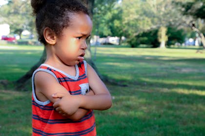 Unhappy child at the park with folded arms