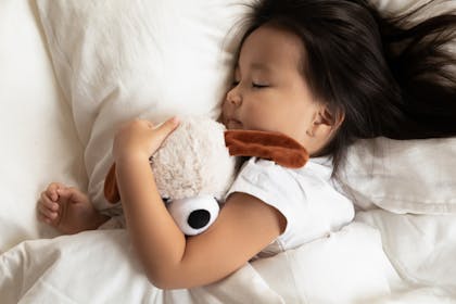 child asleep cuddling teddy