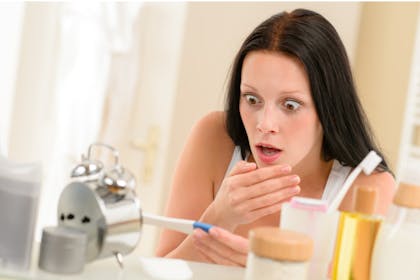 Woman looking shocked at pregnancy test