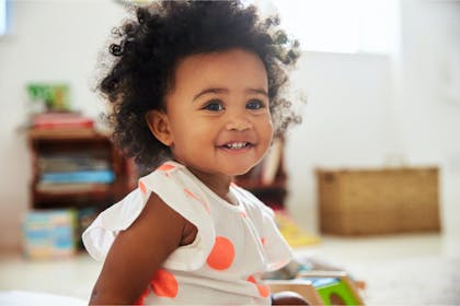 Baby girl in playroom smiling at camera 