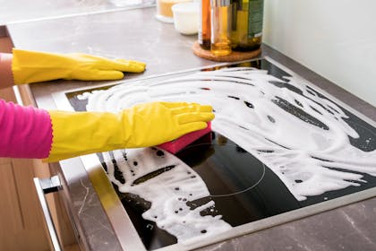 Cleaning stove top with gloves on