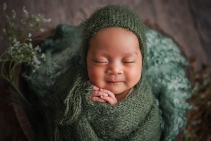 Baby wrapped up in green hat and swaddle