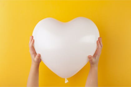 White heart-shaped balloon against yellow background 