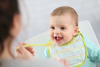 Baby eating puree in high chair