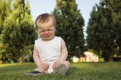 child sitting on grass crying