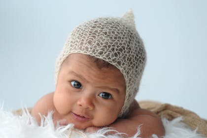 Baby smiling at camera wearing knitted hat 