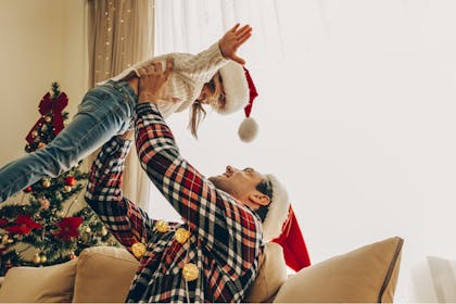 Father lifting daughter in the air wearing Christmas hats