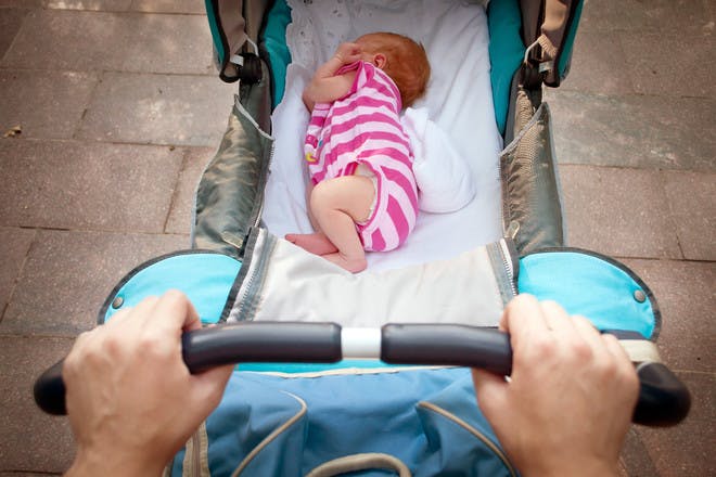 Parent pushing baby in pram