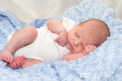 Newborn baby boy asleep on blue blanket