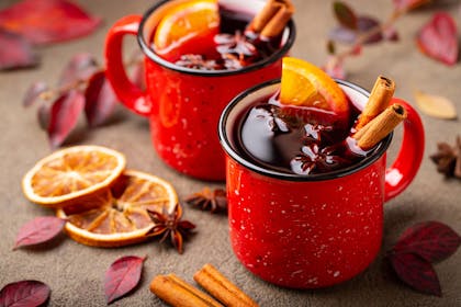 Mugs of mulled wine flavoured with oranges, cloves and cinnamon sticks