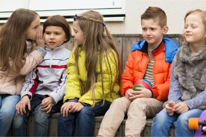 Children sitting in a line playing telephone game 
