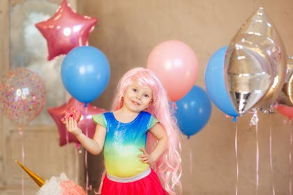 Kid wearing mermaid wig surrounded by balloons at party