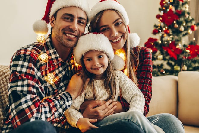 Parents with daughter wearing matching Santa hats for Christmas